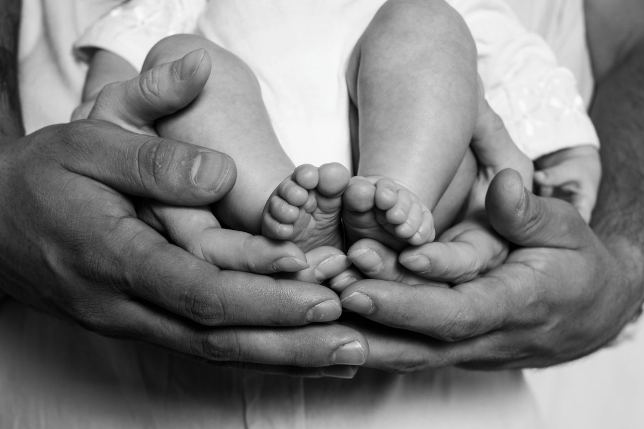 Close-up of adult hands cradling baby feet, symbolizing protection and love.